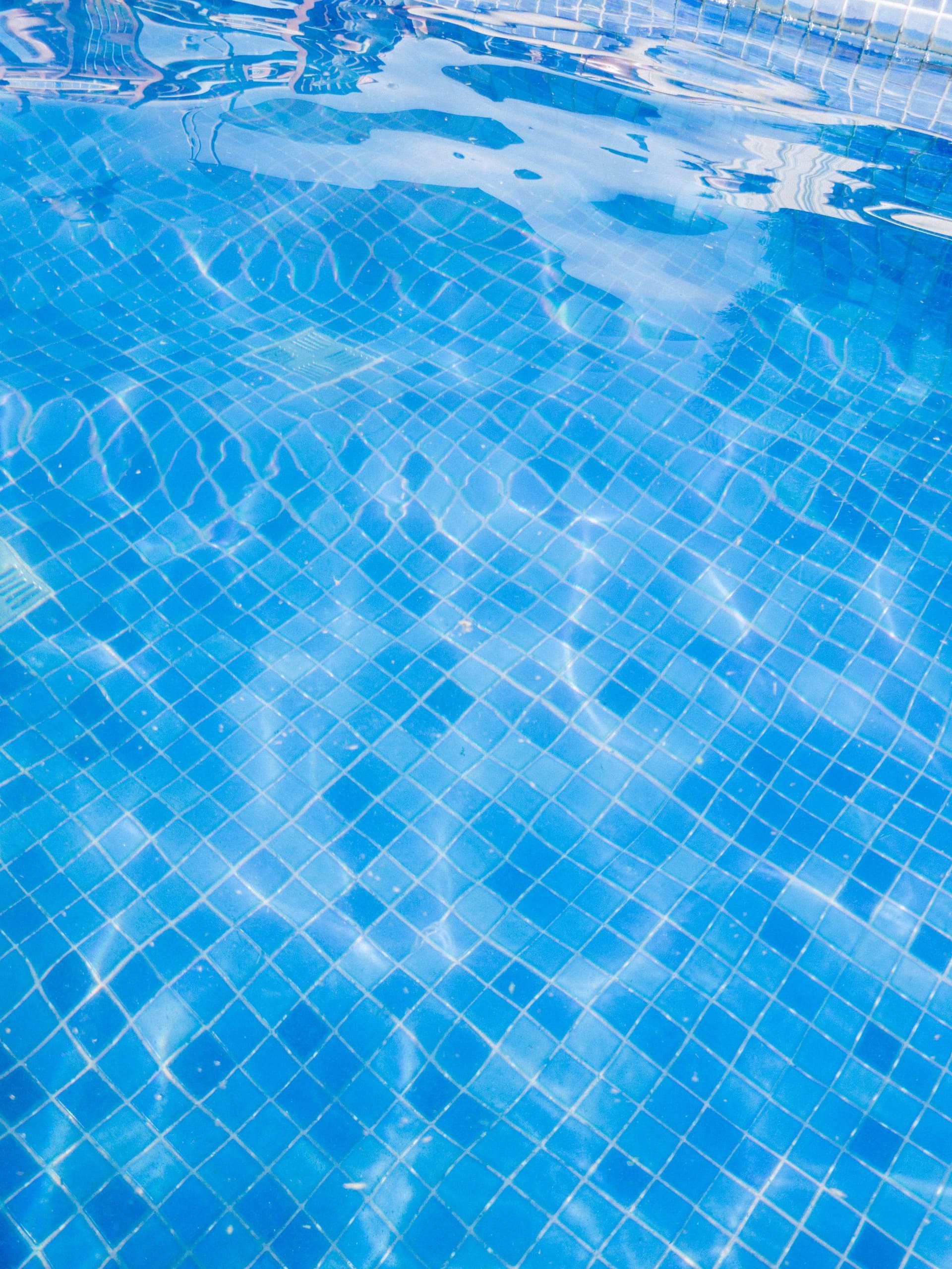 Blue pool tiles seen through clear water in sunlight
